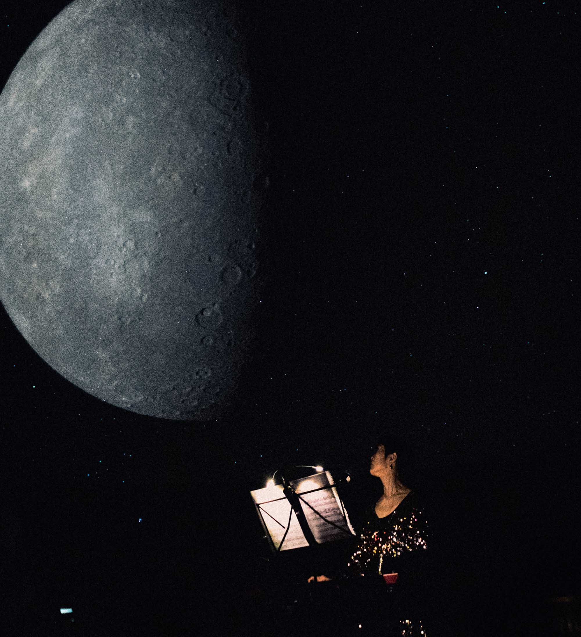 Eine Frau steht an einem beleuchteten Notenständer im Hintergrund ist der halb angestrahlte Mond zu sehen.